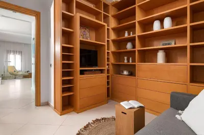 a living room with wooden shelves and a tv at Love White Villa in Ialyssos