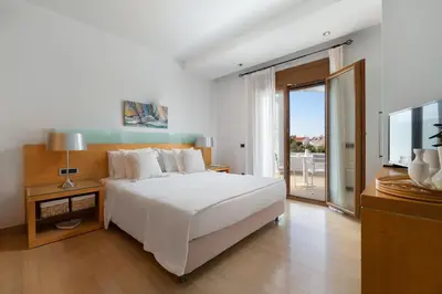 a bedroom with a white bed and a balcony at Love White Villa in Ialyssos