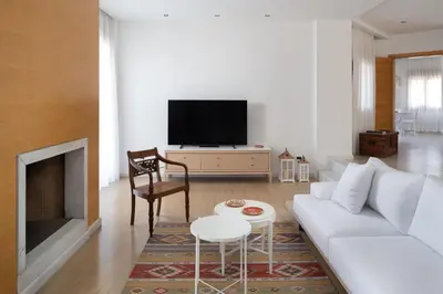 a living room with a white couch and a tv at Love White Villa in Ialyssos