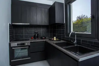 a kitchen with black cabinets and a sink and a window at Villa Indira in Kalithies