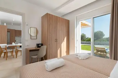 a bedroom with two beds and a table and chairs at OSSIANO POOL VILLAS, Heating Pool, 2 min drive to Haraki Beach & 10 to Lindos in Haraki