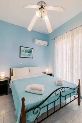 a bedroom with a bed with a ceiling fan at Greek Style Apartment with Jaquzzi & Barbeque in Triánta