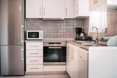 a kitchen with white cabinets and a stainless steel refrigerator at Greek Style Apartment with Jaquzzi & Barbeque in Triánta
