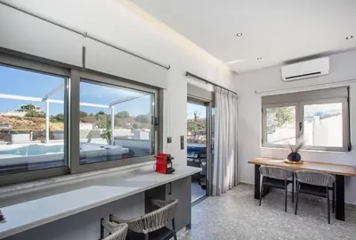 a room with a table and chairs and windows at GM Apartments-Rhodes Luxury Living in Kalithies