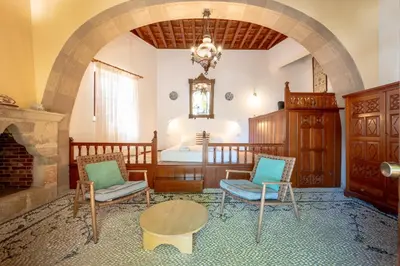 a room with a fireplace and two chairs and a bed at Arte Lindos Suites in Líndos