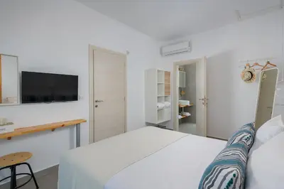 a white bedroom with a bed and a tv on the wall at Niva Kamiros Apartments in Kamiros