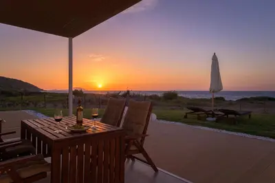 a patio with a table and chairs and a sunset at Niva Kamiros Apartments in Kamiros