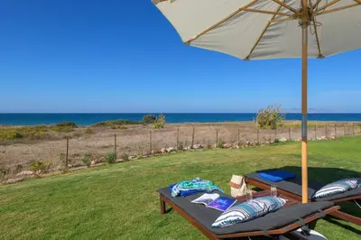a table with an umbrella and two chairs with the ocean at Niva Kamiros Apartments in Kamiros
