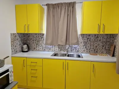 a kitchen with yellow cabinets and a sink at SOLYMAR PRIVE in Archangelos