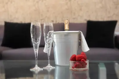 two champagne glasses and a bucket of strawberries on a table at Alina in Triánta