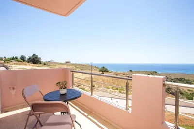 a balcony with a table and chairs and the ocean at Kalypso Sea View Villa in Koskinou