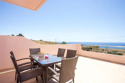a patio with a table and chairs and the ocean at Kalypso Sea View Villa in Koskinou