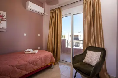 a bedroom with a bed and a chair and a window at Kalypso Sea View Villa in Koskinou