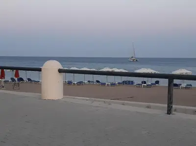 a beach with chairs and umbrellas and the ocean at DIMITRA HOUSE in Rhodes Town