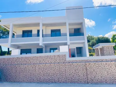 a white building behind a stone wall at Vixen Apartment in Theologos