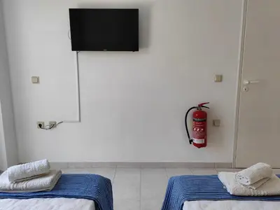 a room with two beds and a fire extinguisher on the wall at East View Appartment (Thanasis 1) in Kalavárda