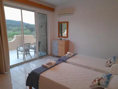 a bedroom with two beds and a balcony at Sunset View Appartment (Thanasis 3) in Kalavárda