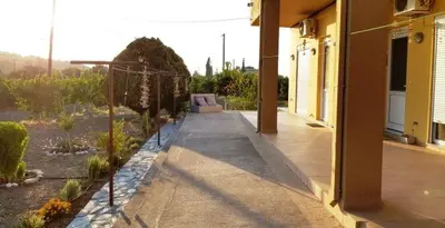 a porch of a house with a garden at Sunset View Appartment (Thanasis 3) in Kalavárda