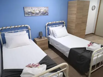 two beds in a room with blue walls at Valantas Garden Suite in Lardos
