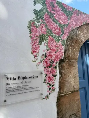 a bunch of flowers on a wall with a sign at Villa Euphrosyne in Líndos