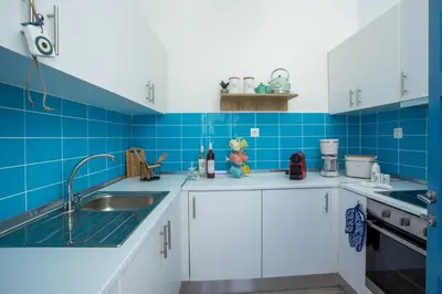 a blue tiled kitchen with white cabinets and a sink at Villa Euphrosyne in Líndos