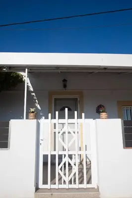 a white gate in front of a white house at Livadi house in Theologos