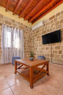 a living room with a table and a tv on a brick wall at Margaritis Luxury Medieval House in Rhodes Town