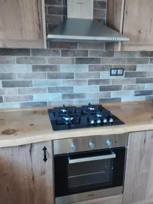a stove top in a kitchen with a brick wall at Olivelia in Ixia