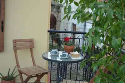 a table with two cups and a chair on a balcony at Summer Knights in Rhodes Town
