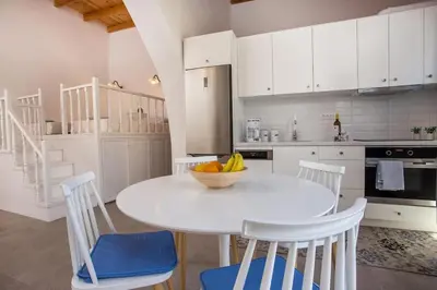 a white kitchen with a white table and chairs at Traditional Luxury House in Kalithies