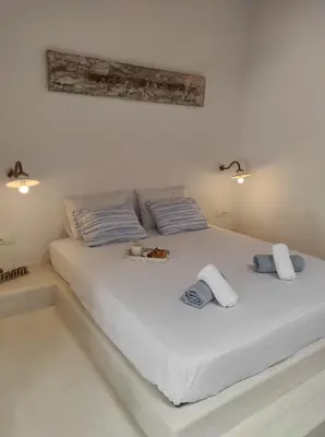 a white bed with blue and white pillows on it at Traditional Luxury House in Kalithies