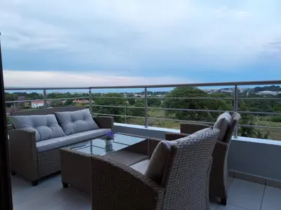 a balcony with wicker chairs and a glass table at Luxury Rhodian Panorama in Ixia