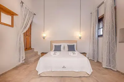 a bedroom with a bed with white sheets and blue pillows at Sala Historical Luxury Suites in Rhodes Town