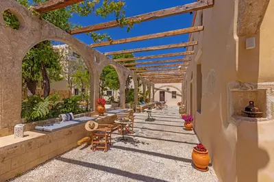 an outdoor patio with tables and chairs under an archway at Sala Historical Luxury Suites in Rhodes Town