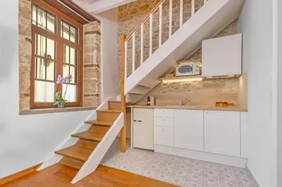 a kitchen with white cabinets and stairs in a loft at Sala Historical Luxury Suites in Rhodes Town