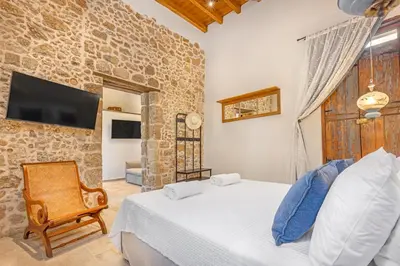 a bedroom with a bed and a tv on a wall at Sala Historical Luxury Suites in Rhodes Town