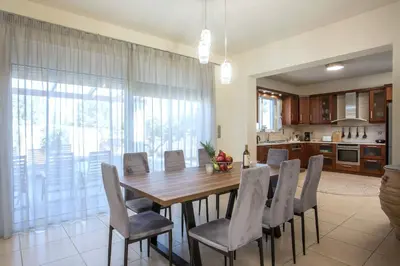 a kitchen and dining room with a wooden table and chairs at Summer Dream Villa in Afantou