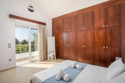 a bedroom with a bed and a large wooden cabinet at Summer Dream Villa in Afantou