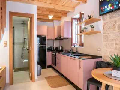 a kitchen with pink cabinets and a glass shower at Captain's Memories Stylish Harbour Apartments in Halki