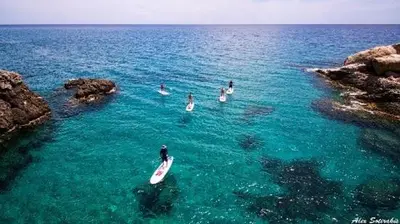 a group of people in the water with a surfboard at Stegna Sunny Beach- up floor in Archangelos