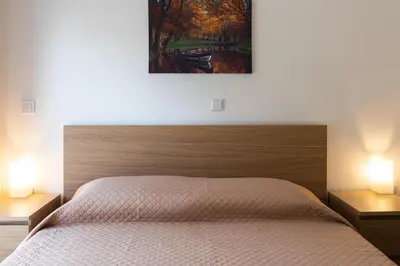 a bedroom with a large bed with two lamps on tables at Kamelia Apartment in Rhodes Town