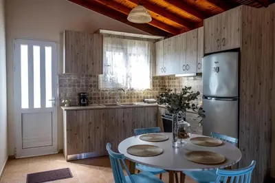 a kitchen with a table with chairs and a refrigerator at G & M Beach House in Haraki