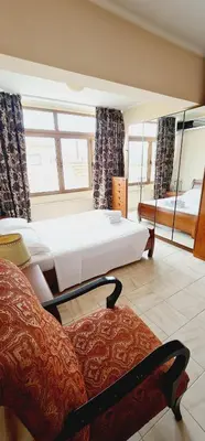 a bedroom with a bed and a chair and windows at Green Sunshine in Theologos
