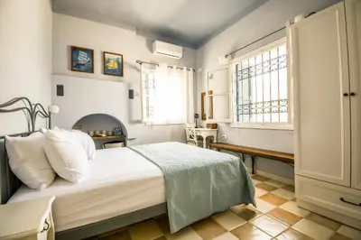 a bedroom with a large white bed and windows at Ponente in Symi