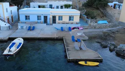 a house with a boat and chairs in the water at Ponente in Symi