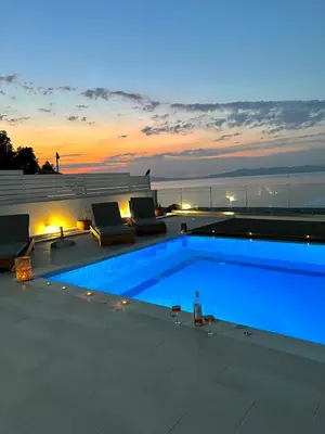 a swimming pool with a sunset in the background at Vaso Beach Front Villa in Ialyssos