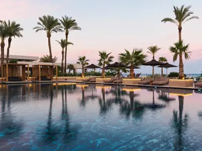 a swimming pool with palm trees and lounge chairs at Ammades All Suites Beach Hotel & Spa - Adults Only in Faliraki