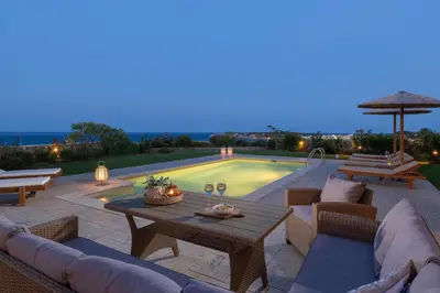 a patio with a table and chairs and a pool at Majestic View Villa in Kolimbia