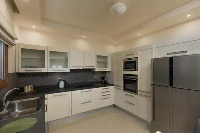 a kitchen with white cabinets and a stainless steel refrigerator at Majestic View Villa in Kolimbia