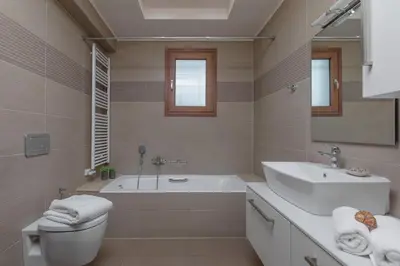 a bathroom with a tub and a sink and a toilet at Majestic View Villa in Kolimbia